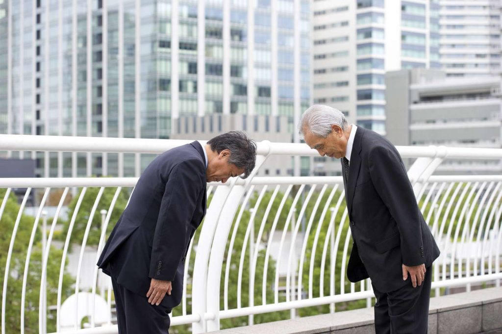 Deux hommes japonais se saluent selon le protocole en vigueur.